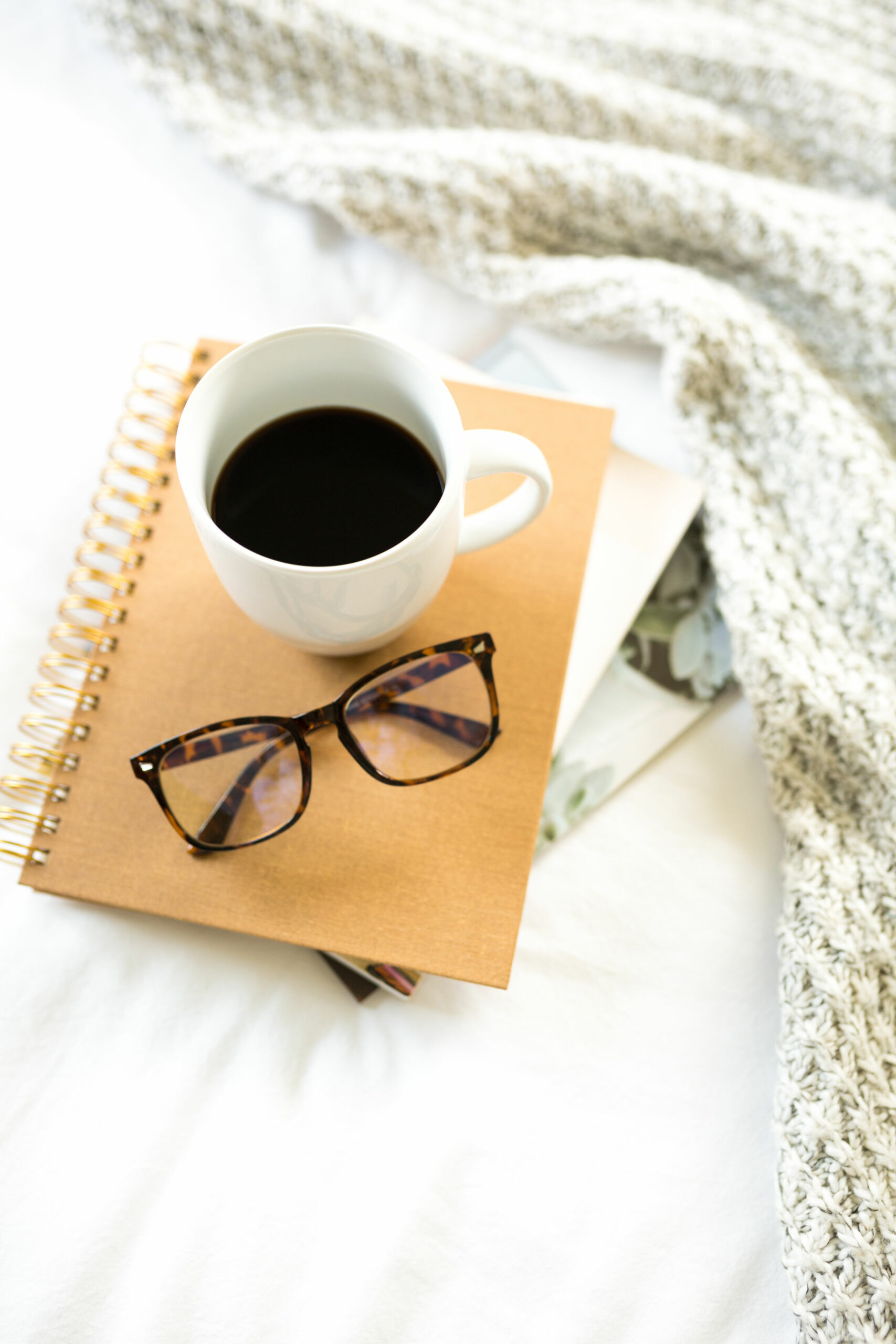 Cup of coffee, reading glasses and notebook