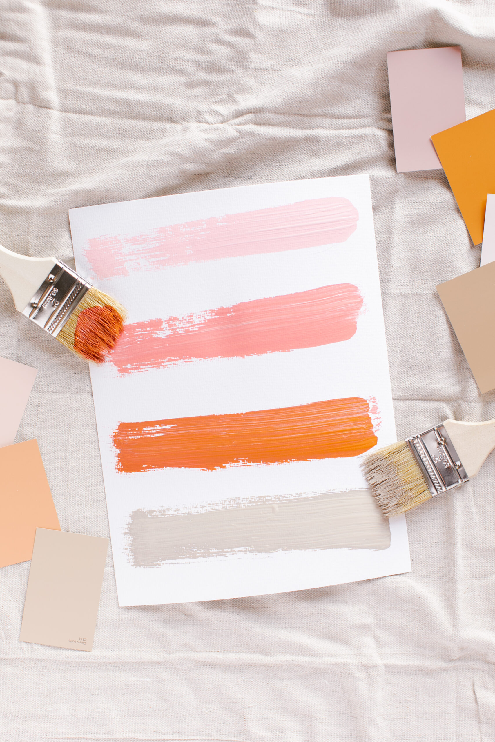 paint brushes with five stripes of multicolored paint on a sheet of paper